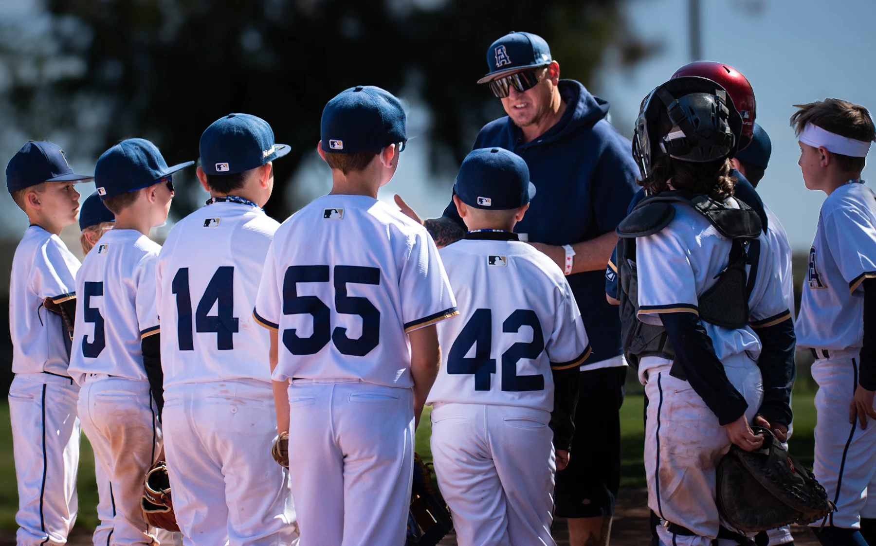 A PA coach talking with a group of players on the field